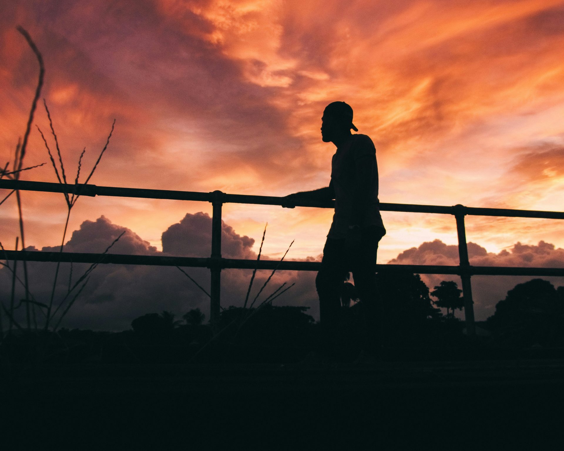 a man walking across a bridge at sunset